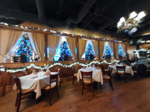 Dining area at Bella Mia Fine Italian Cuisine beautifully decorated with holiday lights and Christmas trees.