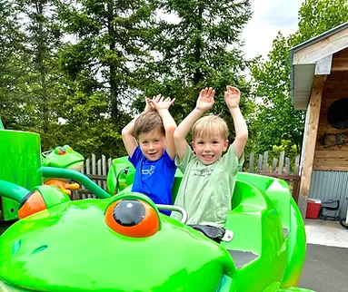 Two children raising their hands while riding the Frog Hopper ride at Bengtson’s Pumpkin Farm.