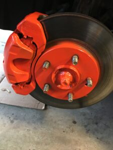 Close-up of a vibrant orange brake caliper and rotor, showcasing automotive repair details relevant to Steve's Pit Stop Mobile Mechanic services.