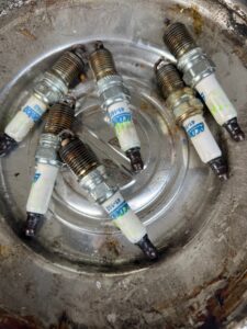 Spark plugs arranged in a metal container, showcasing automotive repair components relevant to Steve's Pit Stop Mobile Mechanic services.