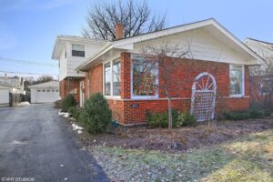 Brick house exterior with a front garden, driveway, and garage, showcasing residential real estate in Harthside, Illinois.