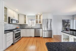 Modern kitchen featuring stainless steel appliances, granite countertops, and hardwood flooring, showcasing a spacious layout ideal for real estate listings in Harthside, Illinois.